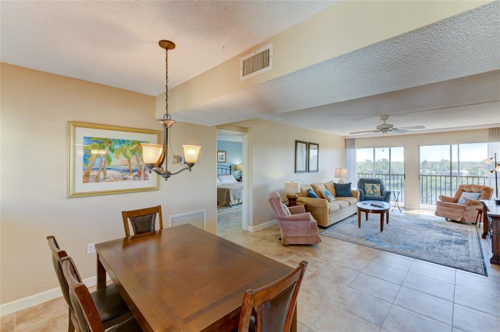 A dining area with a wooden table leads into a living room with tile floors — 3240 GULF OF MEXICO DRIVE UNIT 603, LONGBOAT KEY, FL