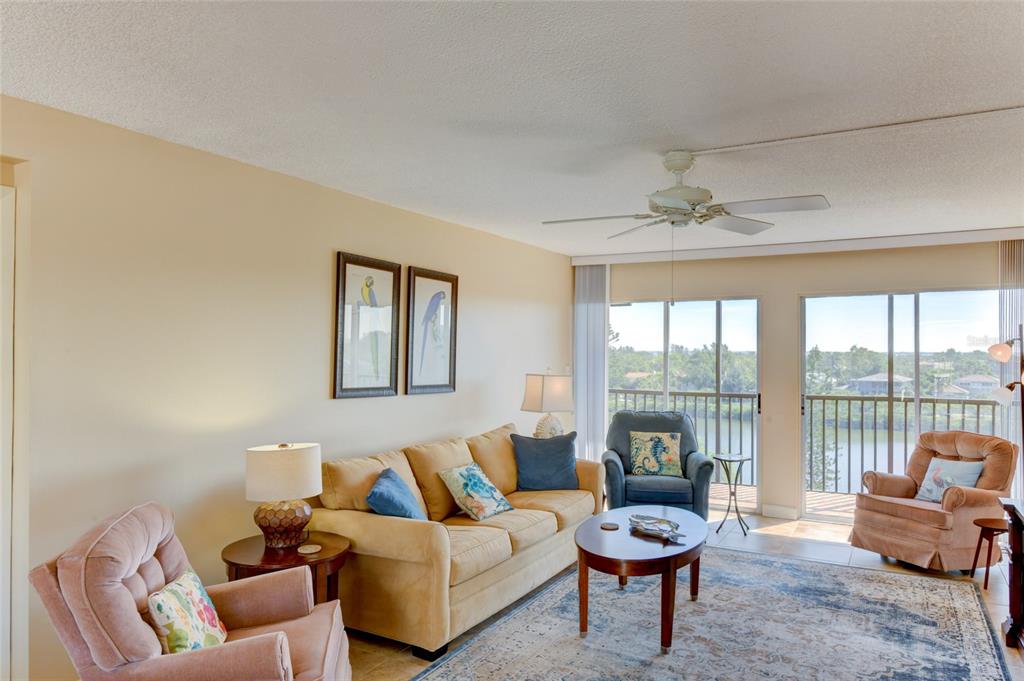 A living room with a beige sofa, two armchairs, a coffee table, and a balcony view — 3240 GULF OF MEXICO DRIVE UNIT 603, LONGBOAT KEY, FL