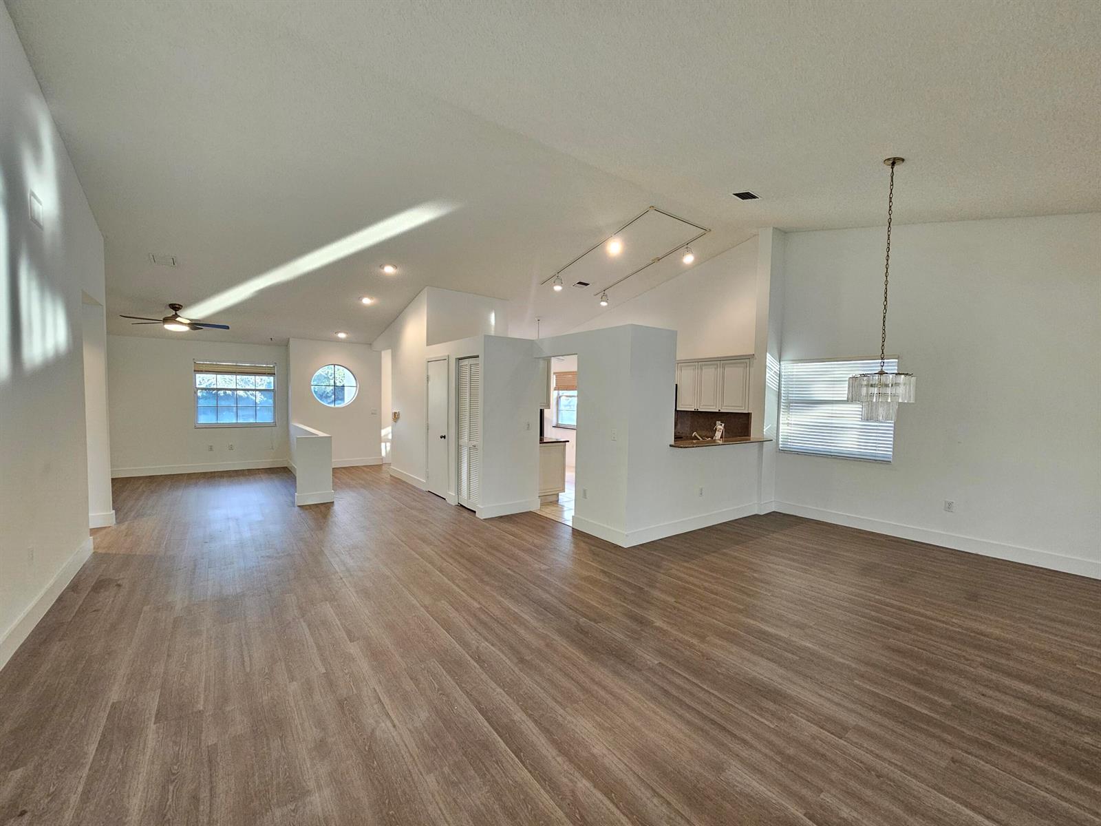 An open-concept living and dining area features vaulted ceilings, wood-look flooring, and a kitchen pass-through — 9637 Shadybrook Drive # 201, Boynton Beach FL 33437, BOYNTON BEACH, FL