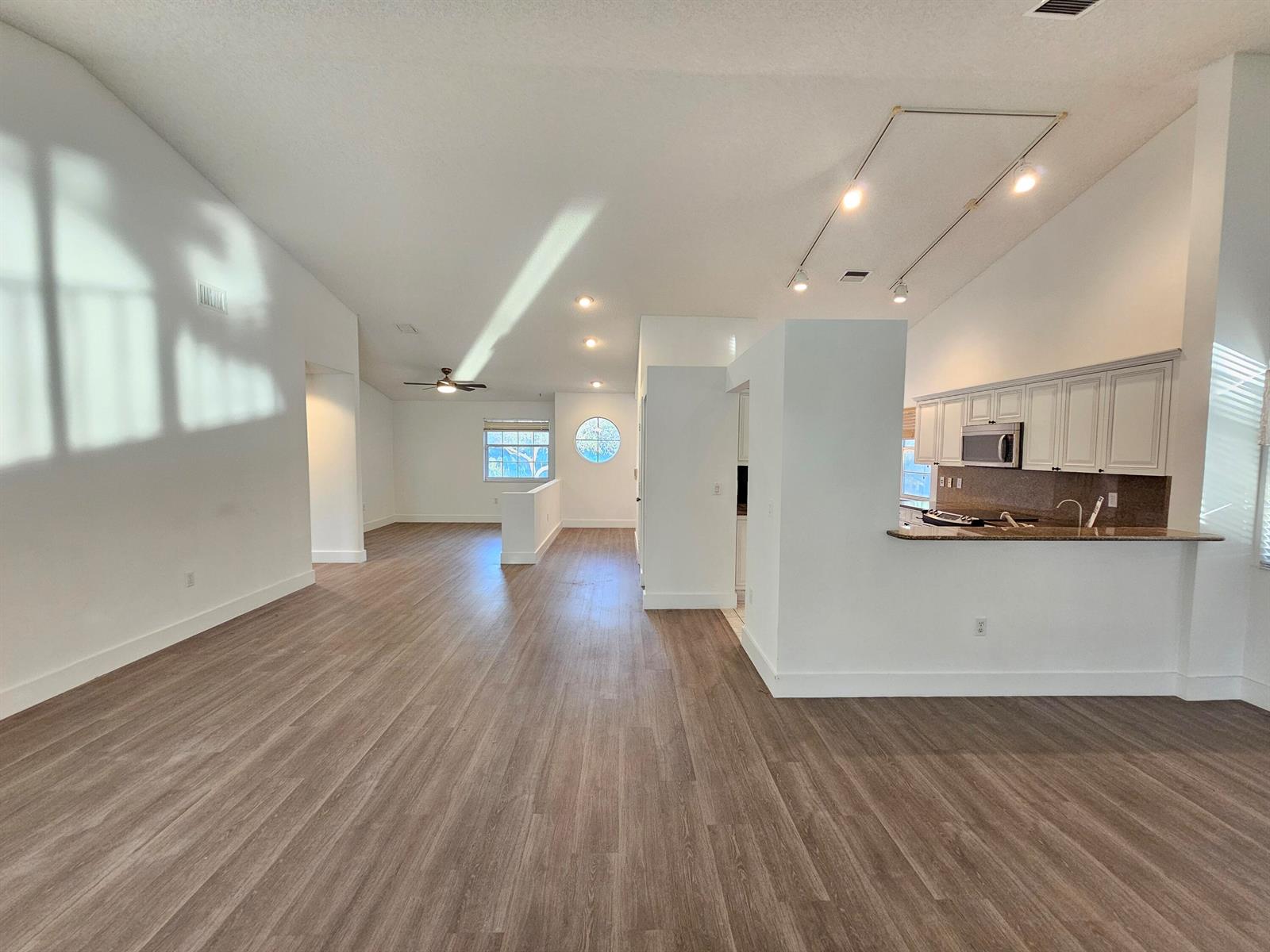 An open-concept living area features white walls, wood-look flooring, and a kitchen with white cabinets — 9637 Shadybrook Drive # 201, Boynton Beach FL 33437, BOYNTON BEACH, FL