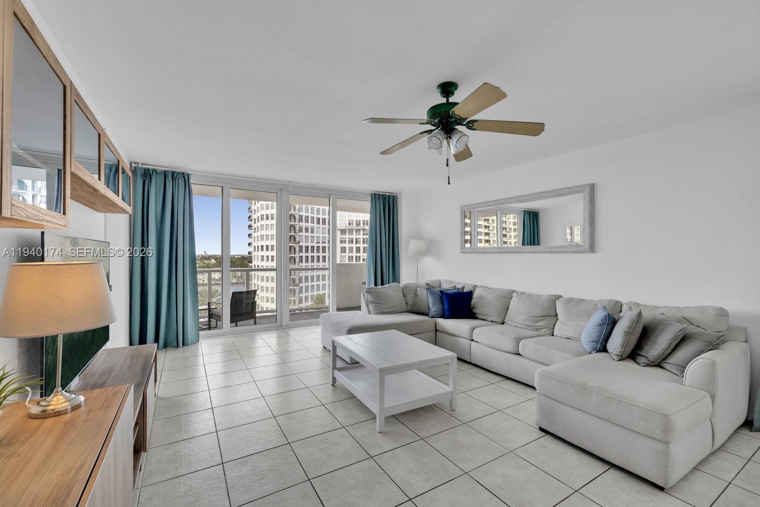 A living room features a large sectional sofa, a coffee table, and floor-to-ceiling windows — 5601 Collins Ave # 825, Miami Beach FL 33140, MIAMI BEACH, FL