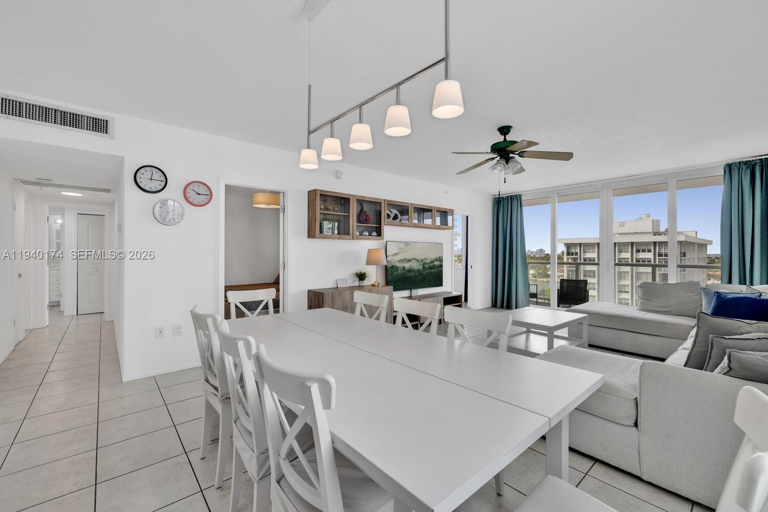 A dining area with a white table and chairs sits adjacent to a living room — 5601 Collins Ave # 825, Miami Beach FL 33140, MIAMI BEACH, FL