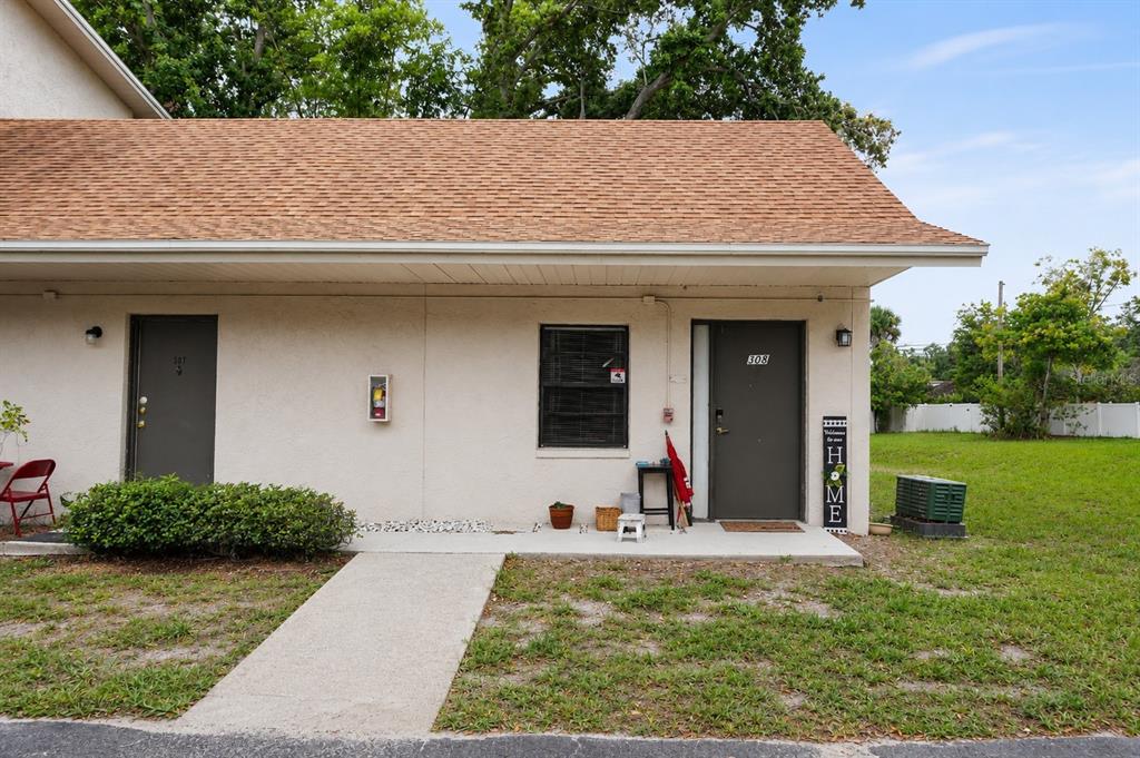 An exterior view of a single-story building with two doors, a window, and a sidewalk — 2142 BRADFORD STREET UNIT 308, CLEARWATER, FL
