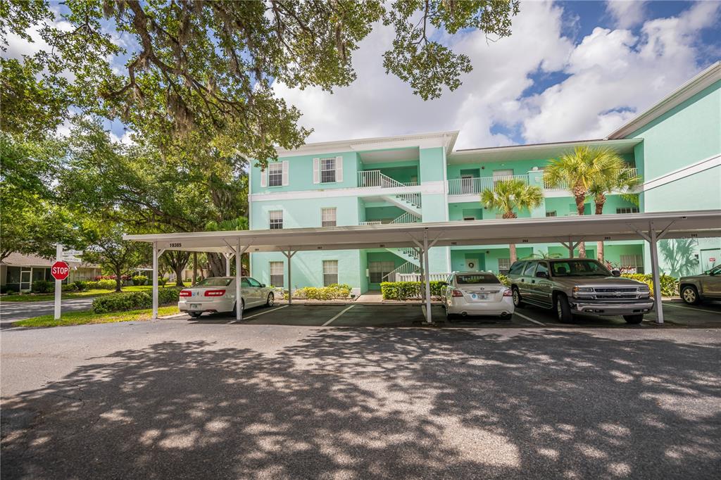 A three-story, light green apartment building with a covered parking area in front — 19385 WATER OAK DRIVE UNIT 301, PORT CHARLOTTE, FL