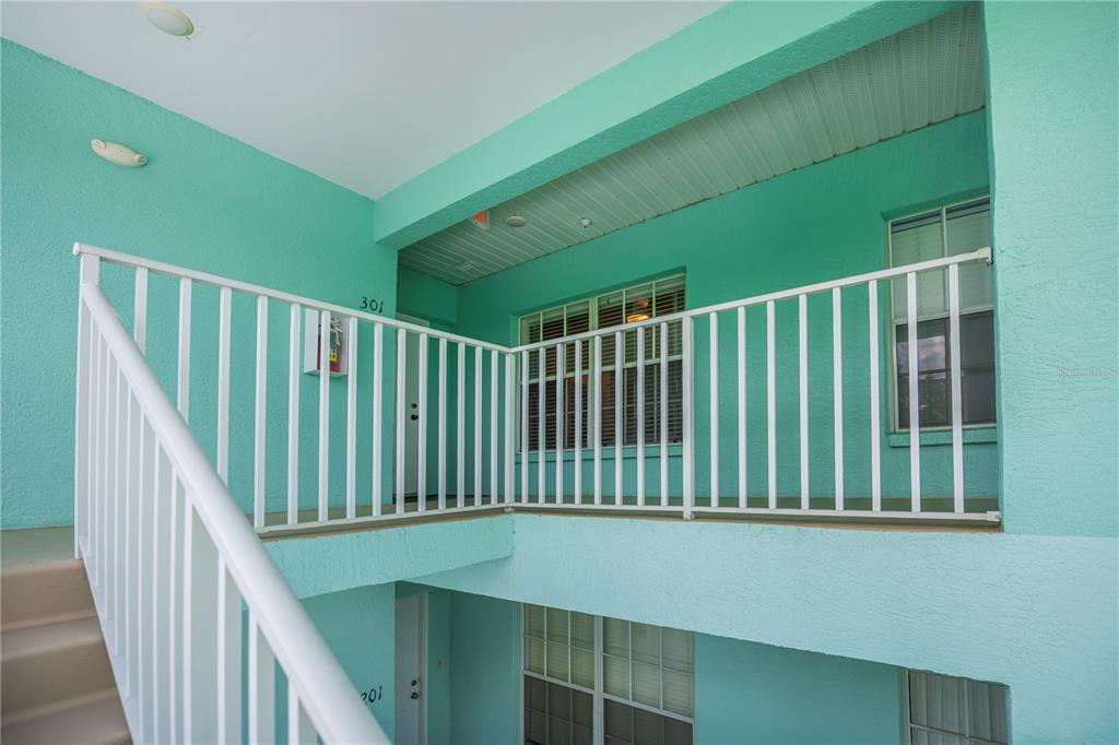 An exterior view of a teal apartment building with white railings and staircases — 19385 WATER OAK DRIVE UNIT 301, PORT CHARLOTTE, FL