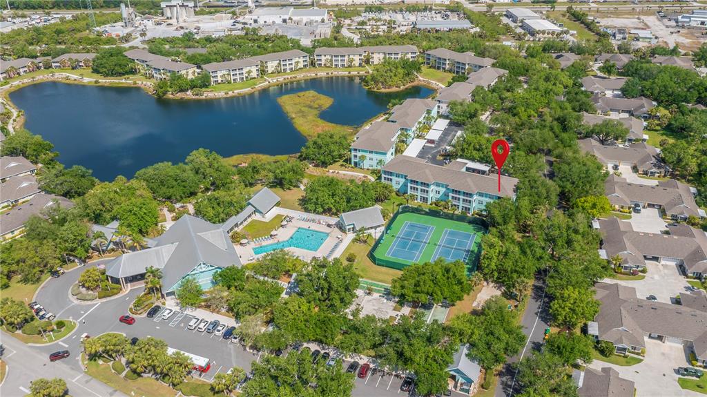 Aerial view of a residential complex featuring a lake, swimming pool, and tennis courts — 19385 WATER OAK DRIVE UNIT 301, PORT CHARLOTTE, FL