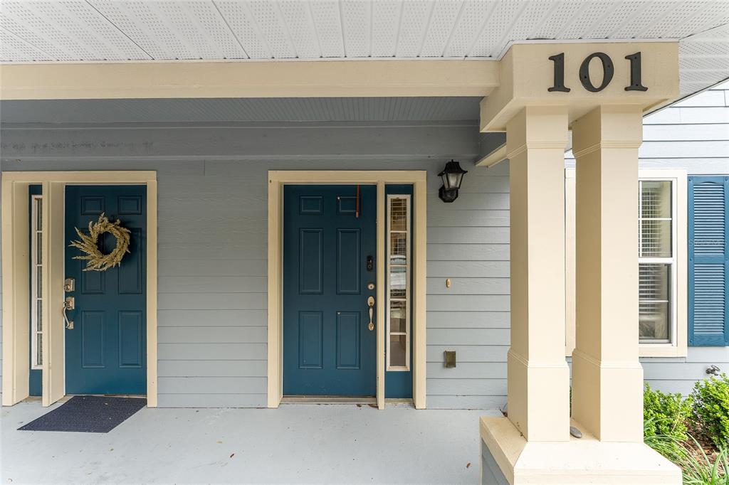 A front porch features two blue doors, a beige column with house number 101, and siding — 2980 SW 35TH PLACE UNIT 101, GAINESVILLE, FL
