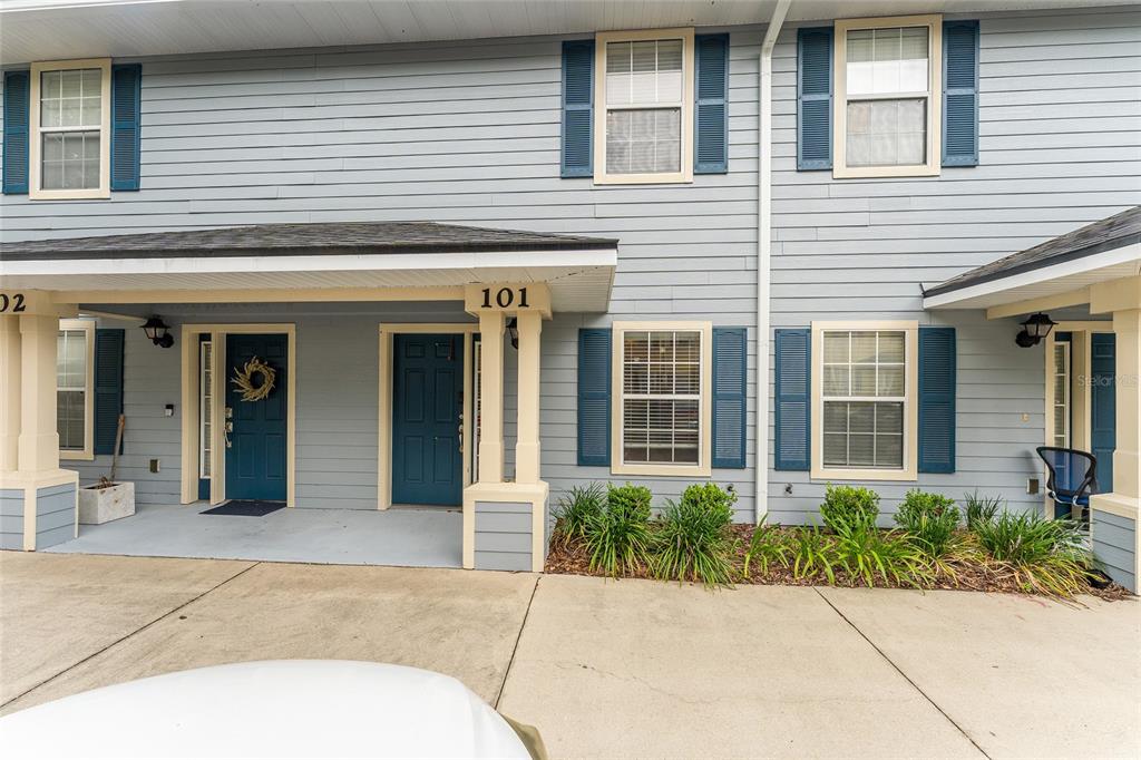 The exterior of a two-story townhouse features blue siding, white trim, and a covered entryway — 2980 SW 35TH PLACE UNIT 101, GAINESVILLE, FL