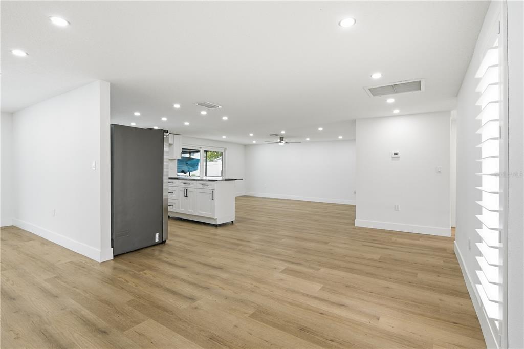 An open-concept living area features light wood flooring, white walls, and a modern kitchen island — 9911 ISLAND HARBOR DRIVE, PORT RICHEY, FL