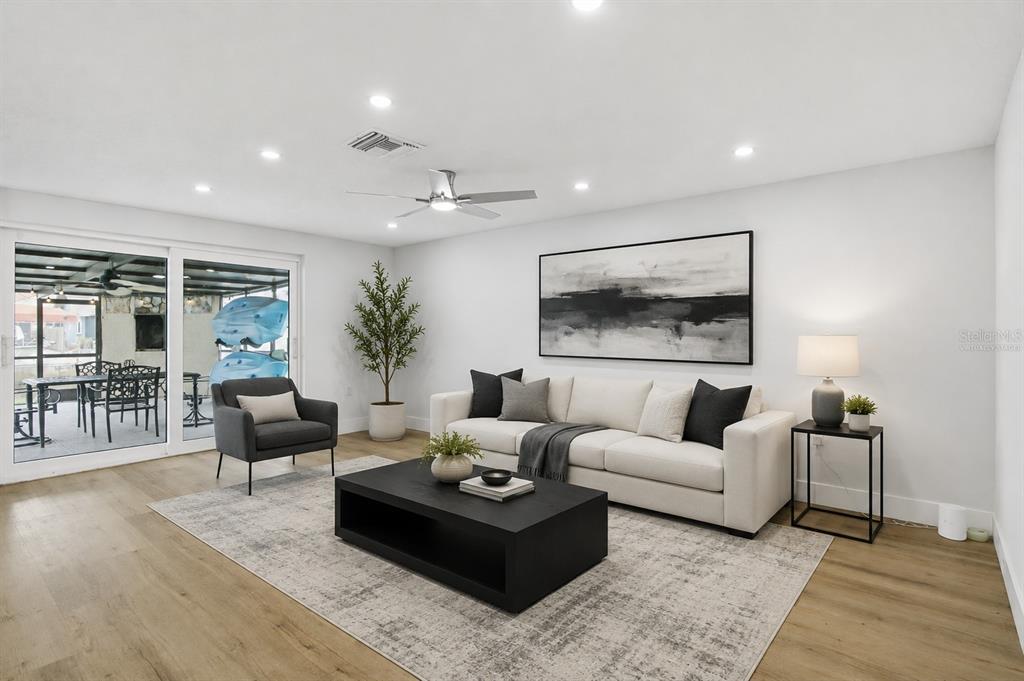 A living room features a white sofa, black coffee table, gray armchair, and sliding glass doors — 9911 ISLAND HARBOR DRIVE, PORT RICHEY, FL