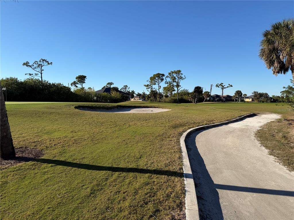 A golf course view featuring a sand bunker, green grass, and a paved cart path — 2 PINE VALLEY PL, ROTONDA WEST, FL