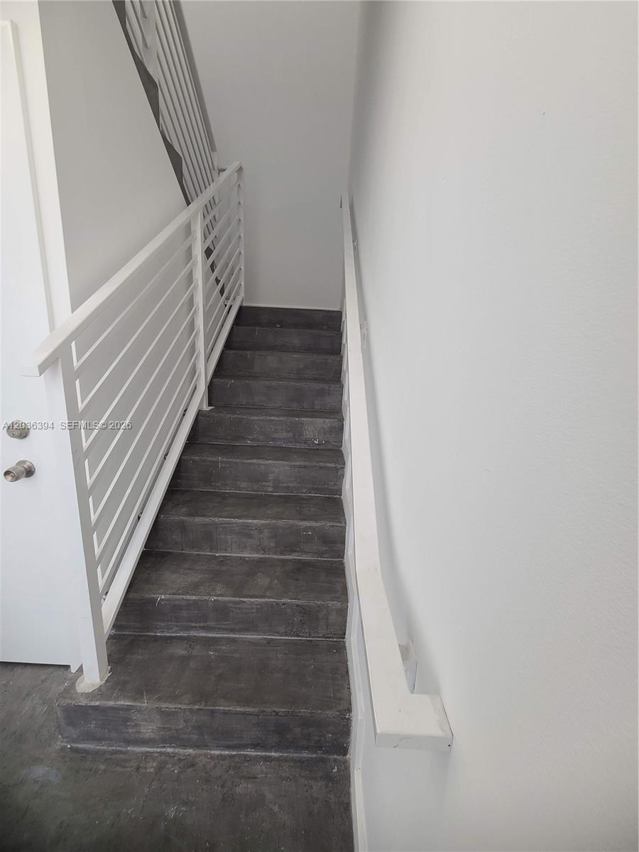 A staircase with dark fiber-cement steps and white railings leads upward against white walls — 825 Michigan Ave # 7, Miami Beach FL 33139, MIAMI BEACH, FL