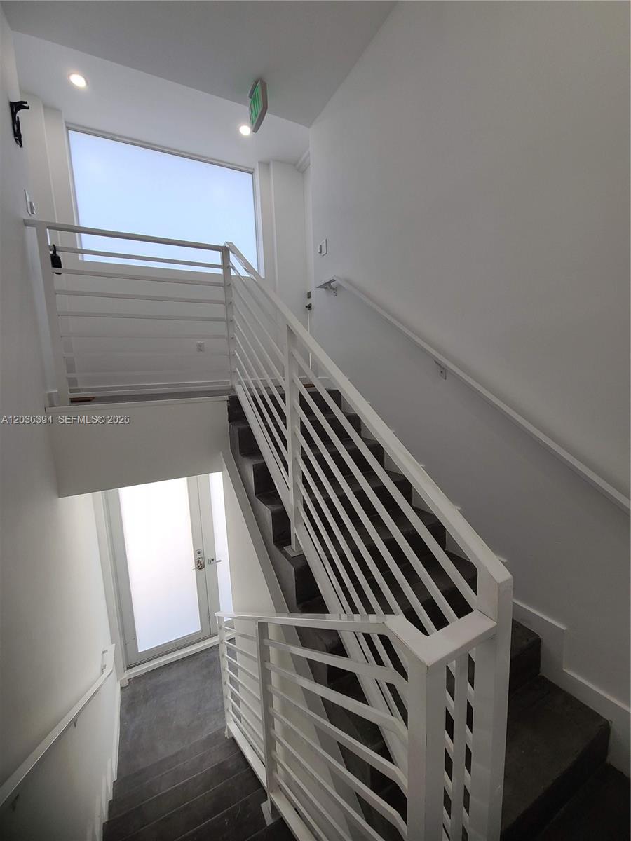 A white metal staircase with dark treads leads to a landing with a glass door — 825 Michigan Ave # 7, Miami Beach FL 33139, MIAMI BEACH, FL