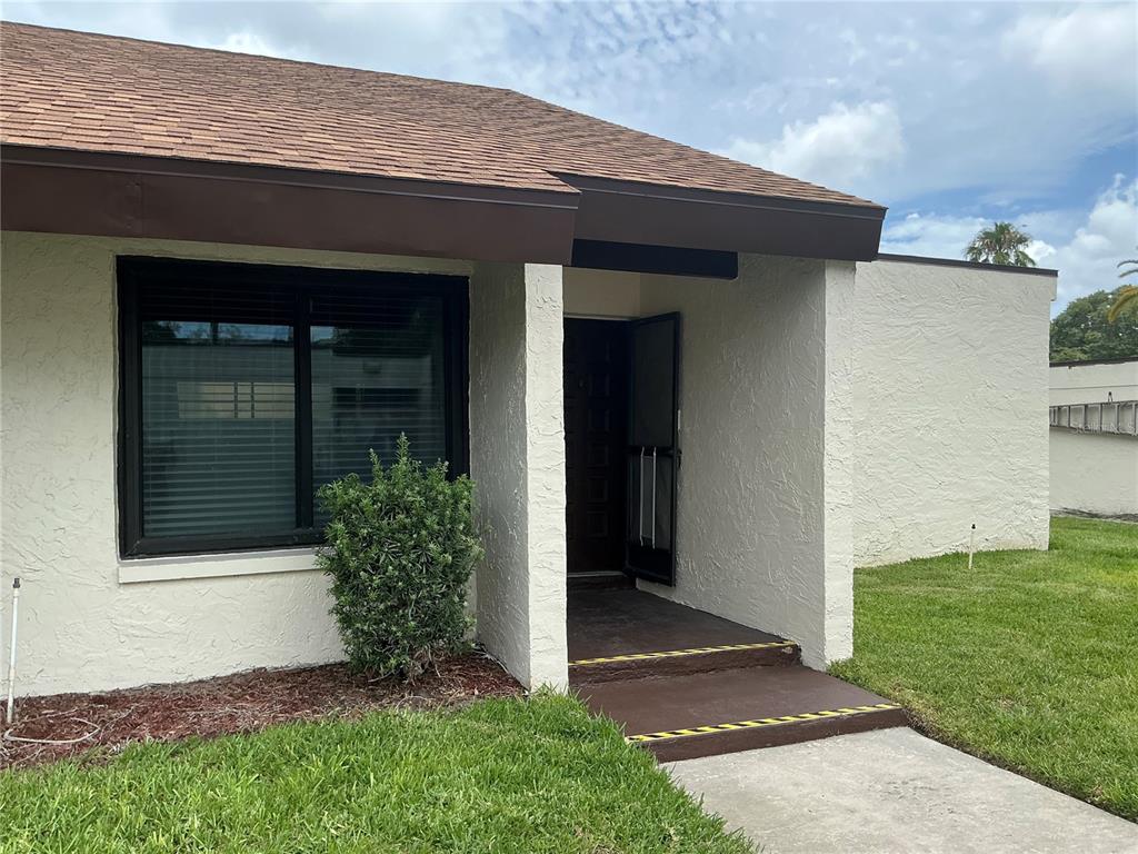 A single-story house with a brown shingled roof, white stucco walls, and a recessed entrance — 2207 BELLEAIR ROAD UNIT B22, CLEARWATER, FL