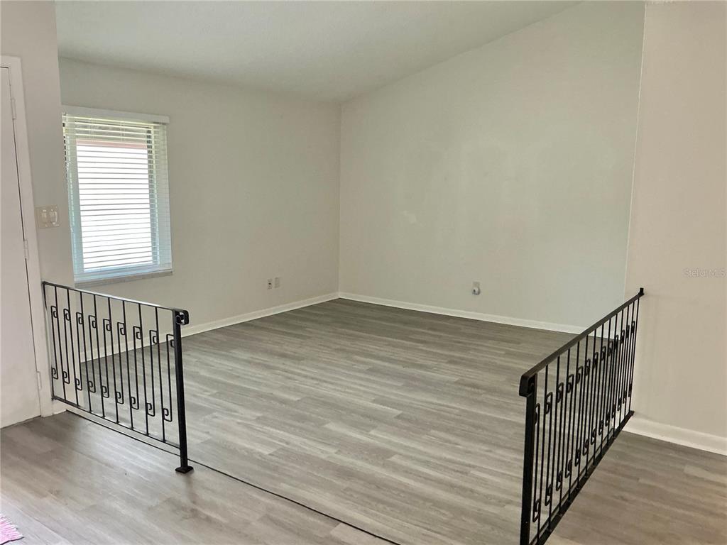 A sunken living area features light-colored wood-look flooring and black metal railings — 2207 BELLEAIR ROAD UNIT B22, CLEARWATER, FL