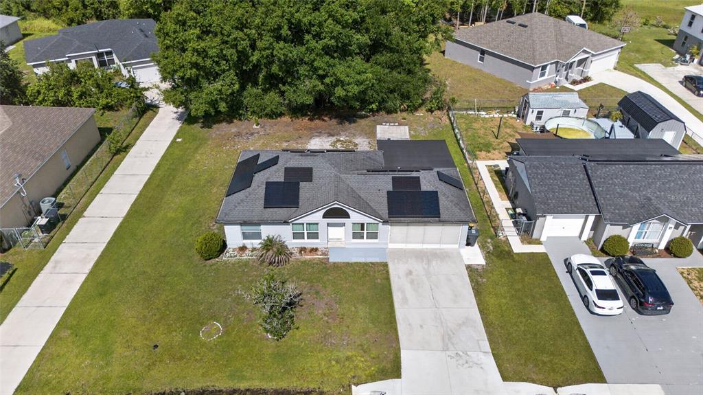 A single-story gray house with a concrete driveway, solar panels, and a two-car garage — 610 JAGUAR COURT, KISSIMMEE, FL