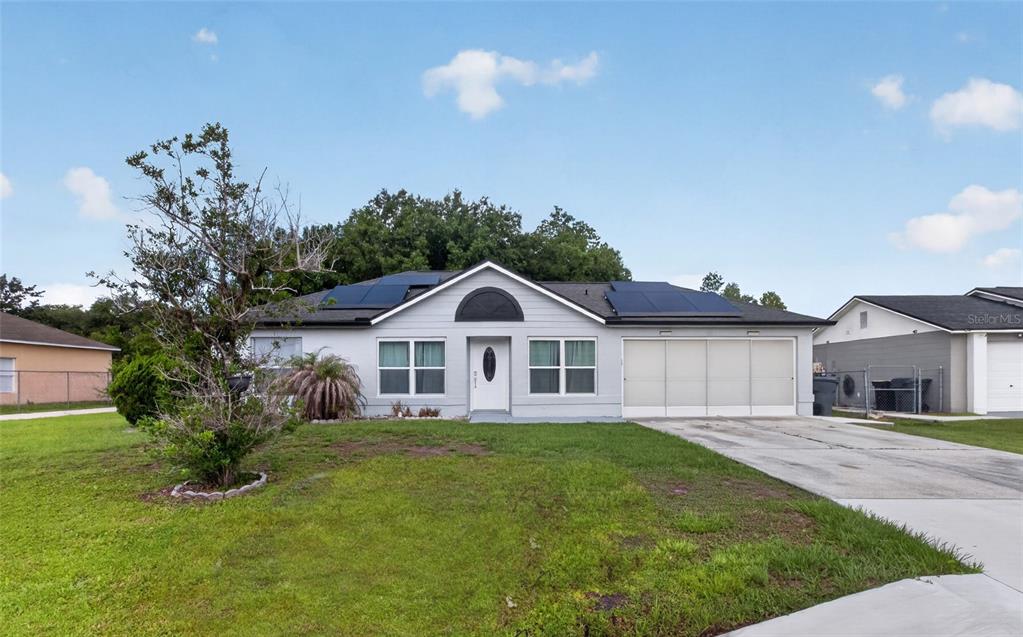 A single-story house with a gray exterior, solar panels on the roof, and a driveway — 610 JAGUAR COURT, KISSIMMEE, FL