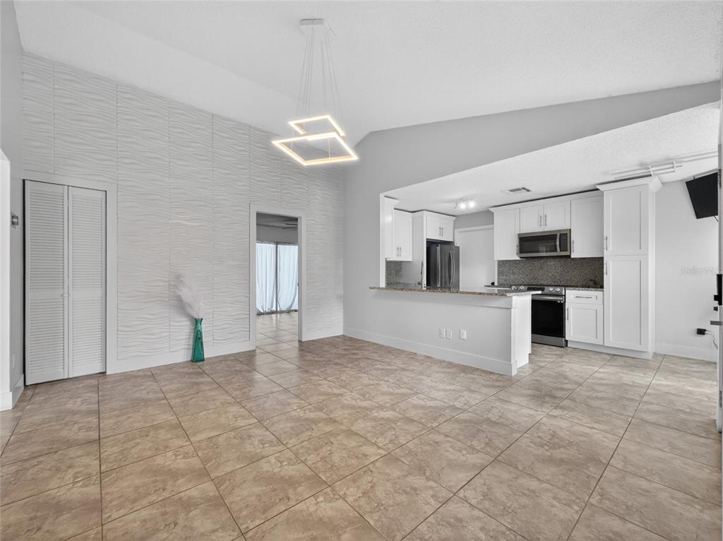 A kitchen with granite countertops and white cabinets overlooks a tiled dining area — 610 JAGUAR COURT, KISSIMMEE, FL