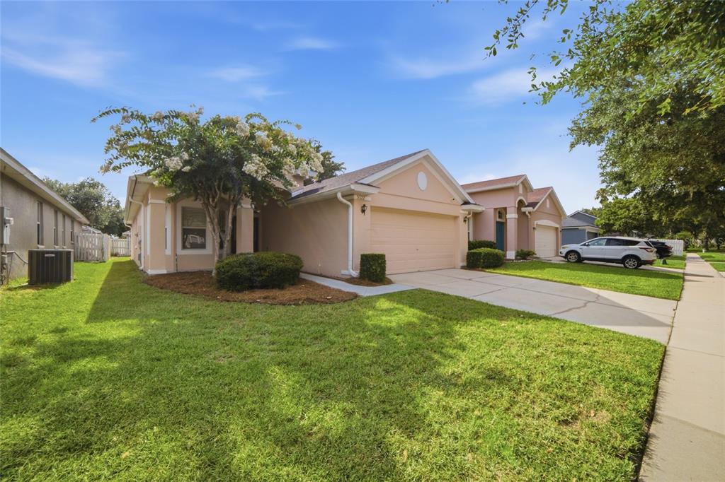 A single-story peach-colored house with a two-car garage and a front lawn — 5322 SANTA ANA DRIVE, ORLANDO, FL