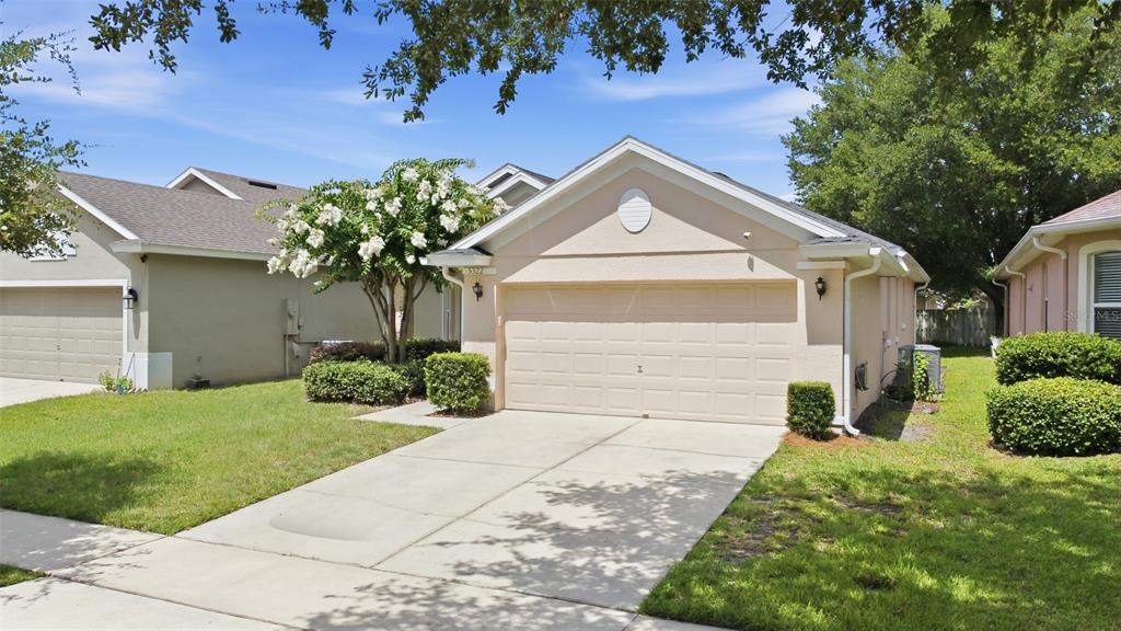 A single-story house with a beige stucco exterior, a two-car garage, and a concrete driveway — 5322 SANTA ANA DRIVE, ORLANDO, FL