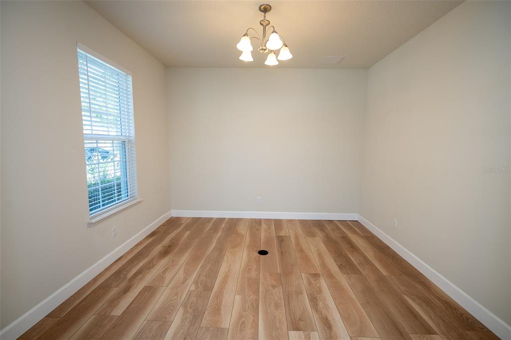 An empty dining room features light wood-look flooring, a window with blinds, and a chandelier — 12077 ULETA LANE, ORLANDO, FL
