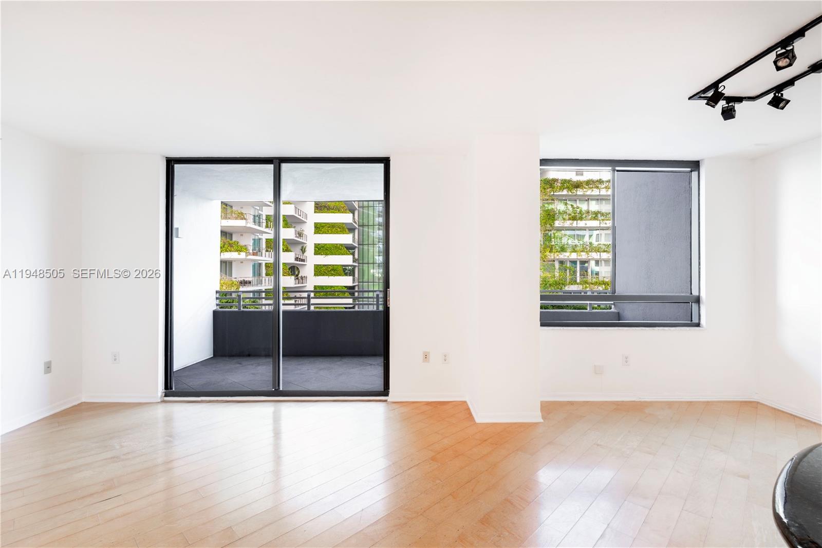 An empty room with light wood floors, a balcony, and track lighting on the ceiling — 1330 West Ave # 610, Miami Beach FL 33139, MIAMI BEACH, FL