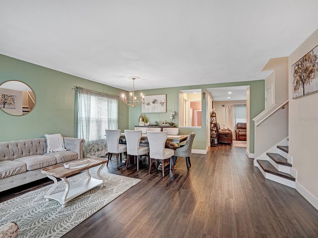 A dining area and living room feature sage green walls, dark wood floors, and stairs — 16755 SUNRISE VISTA DRIVE, CLERMONT, FL