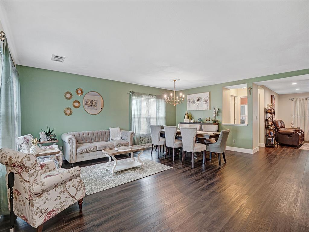A living and dining room with sage green walls, dark wood floors, and floral furniture — 16755 SUNRISE VISTA DRIVE, CLERMONT, FL