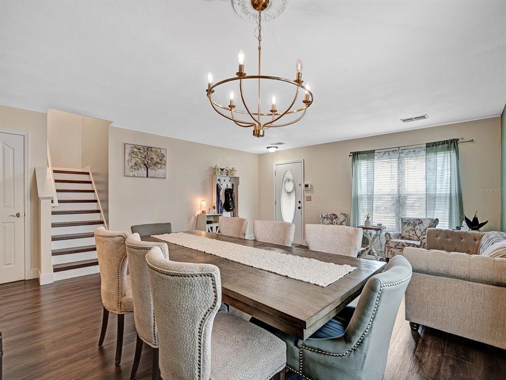 A dining room features a wooden table, upholstered chairs, a chandelier, and a staircase — 16755 SUNRISE VISTA DRIVE, CLERMONT, FL