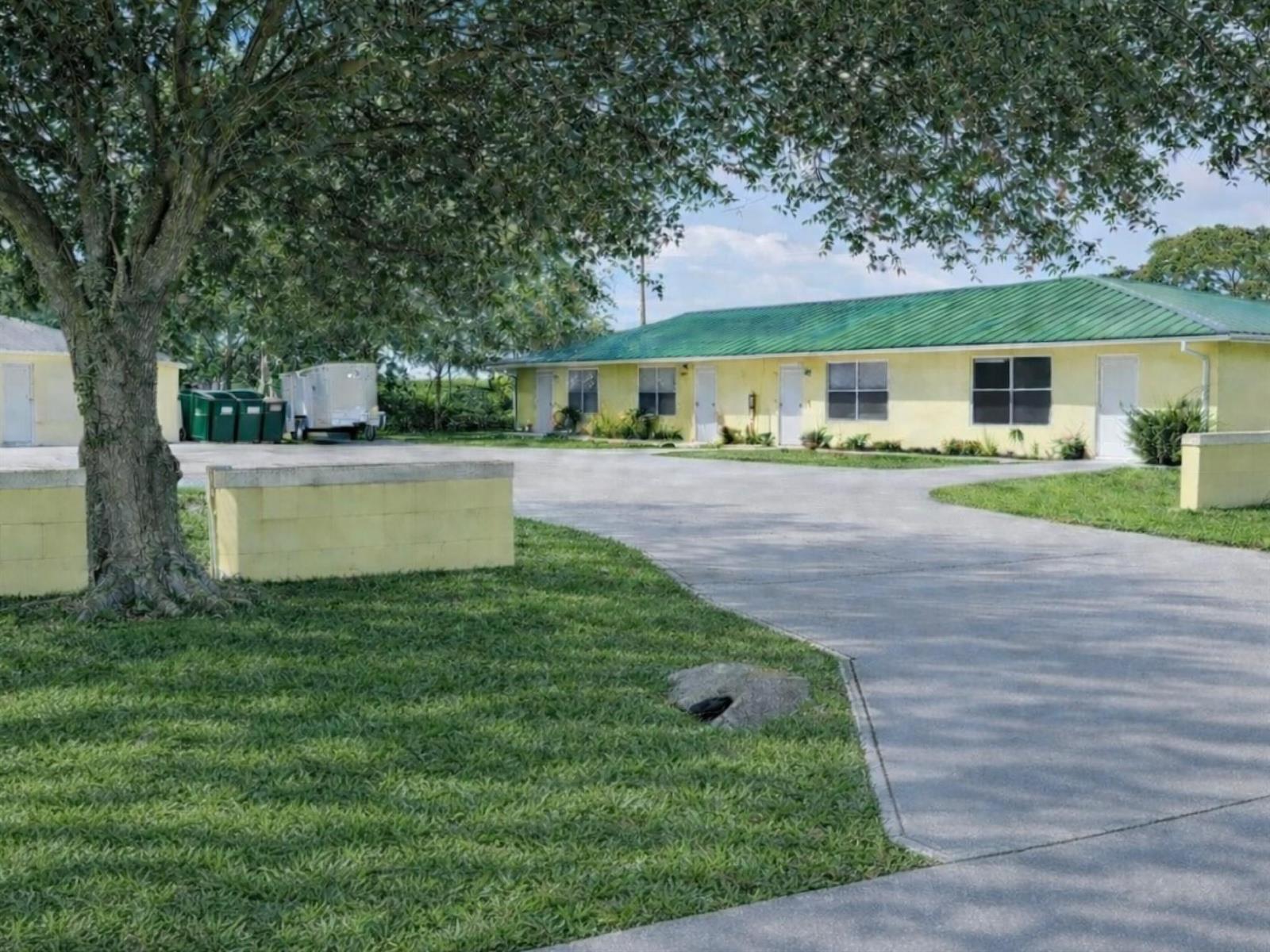 A yellow single-story building with a green metal roof sits behind a paved driveway — 951 King Orange Drive, Fort Pierce FL 34982, FORT PIERCE, FL
