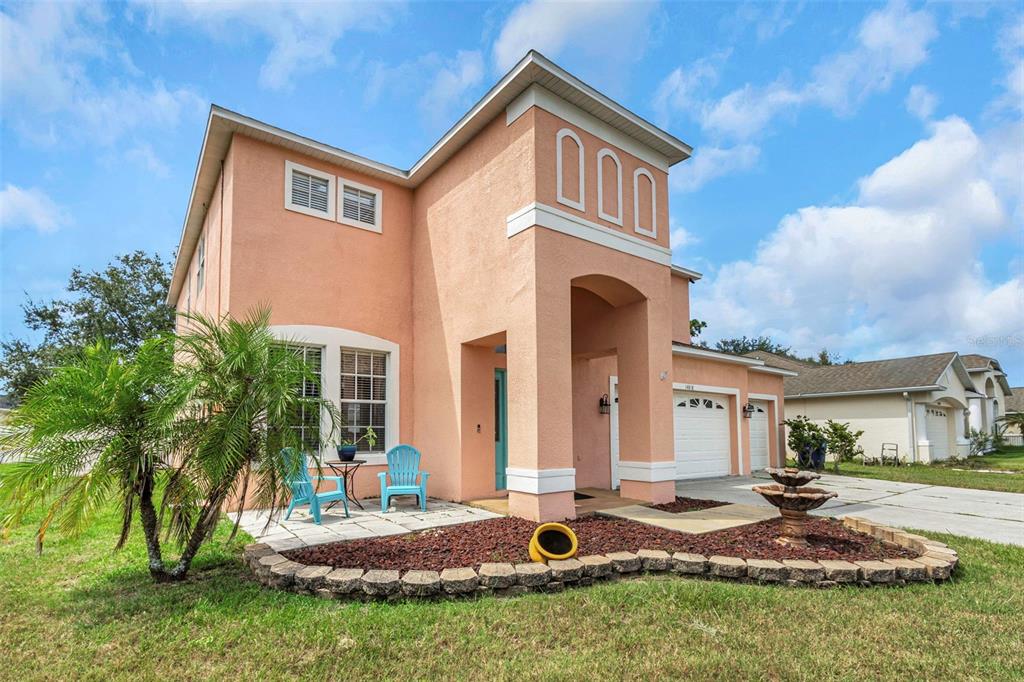 A two-story peach-colored house with a front patio, palm tree, and attached two-car garage — 14818 EDGEMERE DRIVE, SPRING HILL, FL