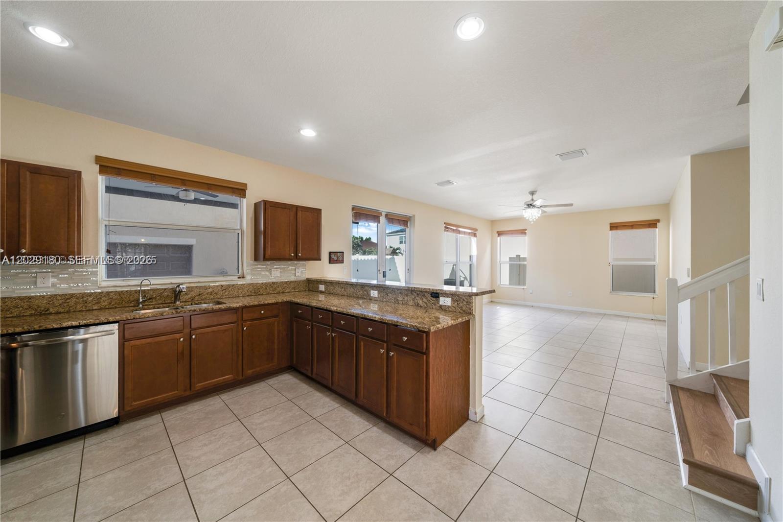 A kitchen with wood cabinets and granite countertops opens to a tiled living area — 16946 SW 90th Terrace Circle, Miami FL 33196, MIAMI, FL