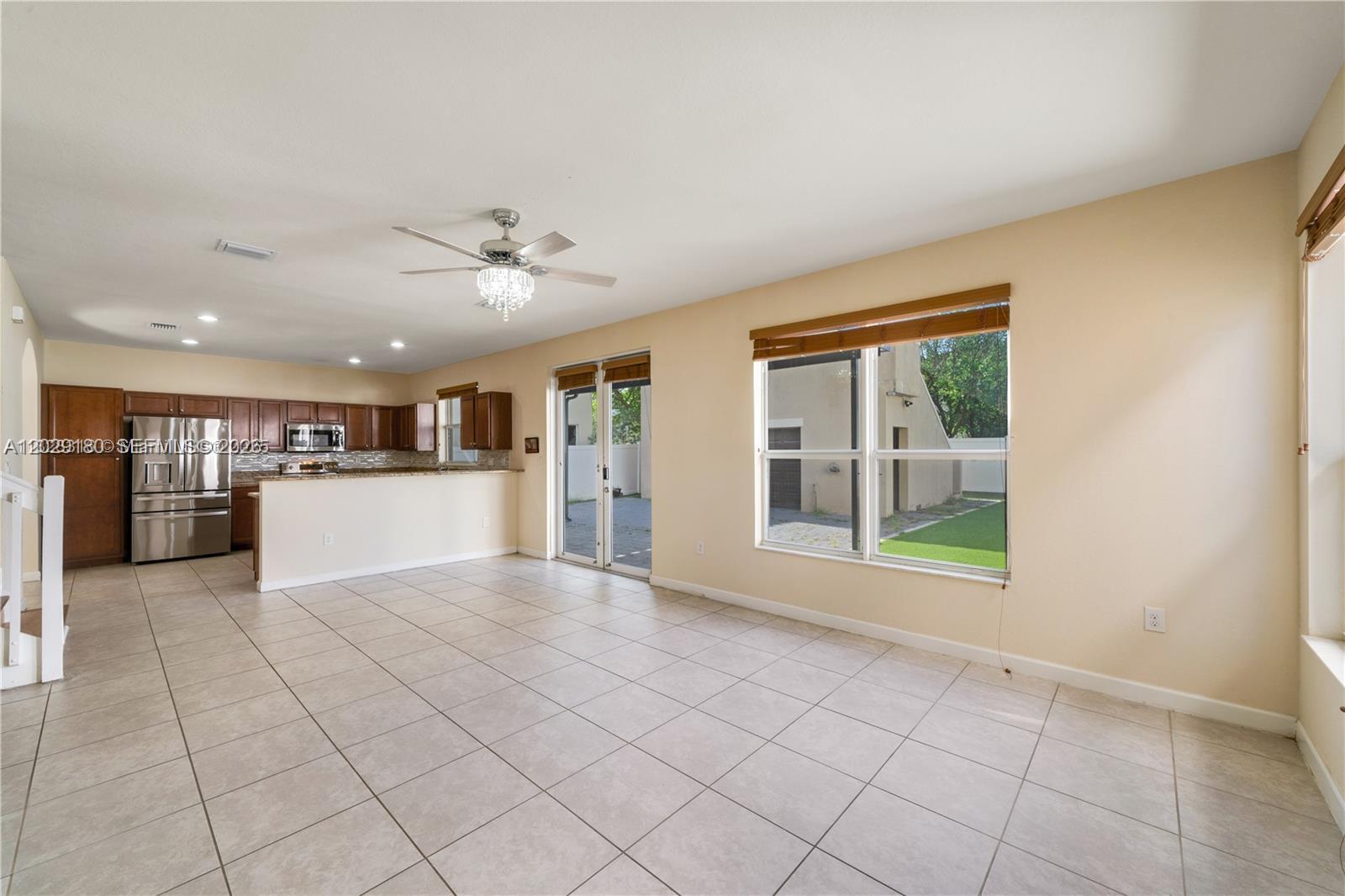 An open-concept living area features tile flooring, a kitchen with wood cabinets, and sliding doors — 16946 SW 90th Terrace Circle, Miami FL 33196, MIAMI, FL