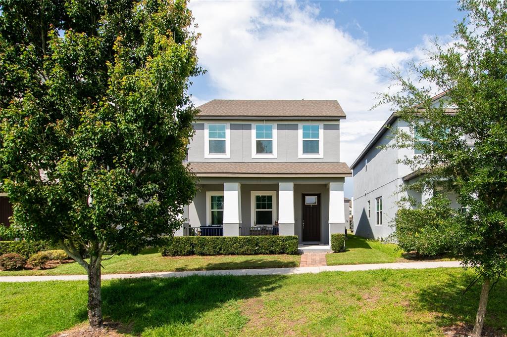 A two-story gray house with a front porch, white columns, and a manicured hedge — 2241 WHITE FEATHER LOOP, WINTER GARDEN, FL