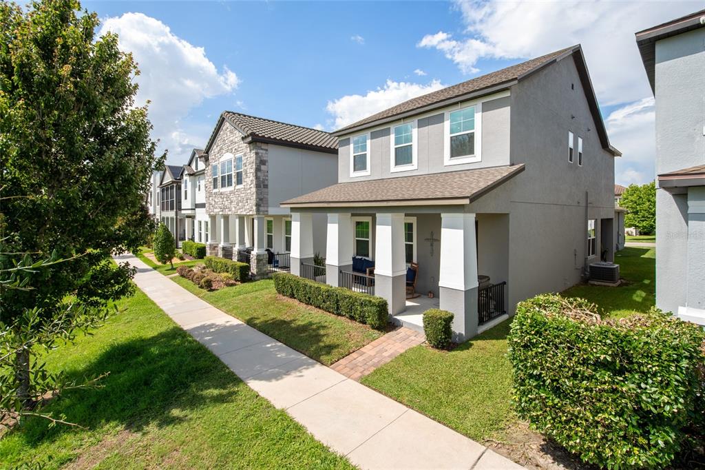 A row of two-story suburban houses with front porches and manicured lawns along a sidewalk — 2241 WHITE FEATHER LOOP, WINTER GARDEN, FL