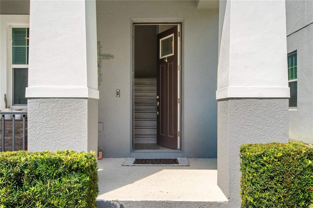 A front porch with a dark brown door leads into a home with interior stairs — 2241 WHITE FEATHER LOOP, WINTER GARDEN, FL