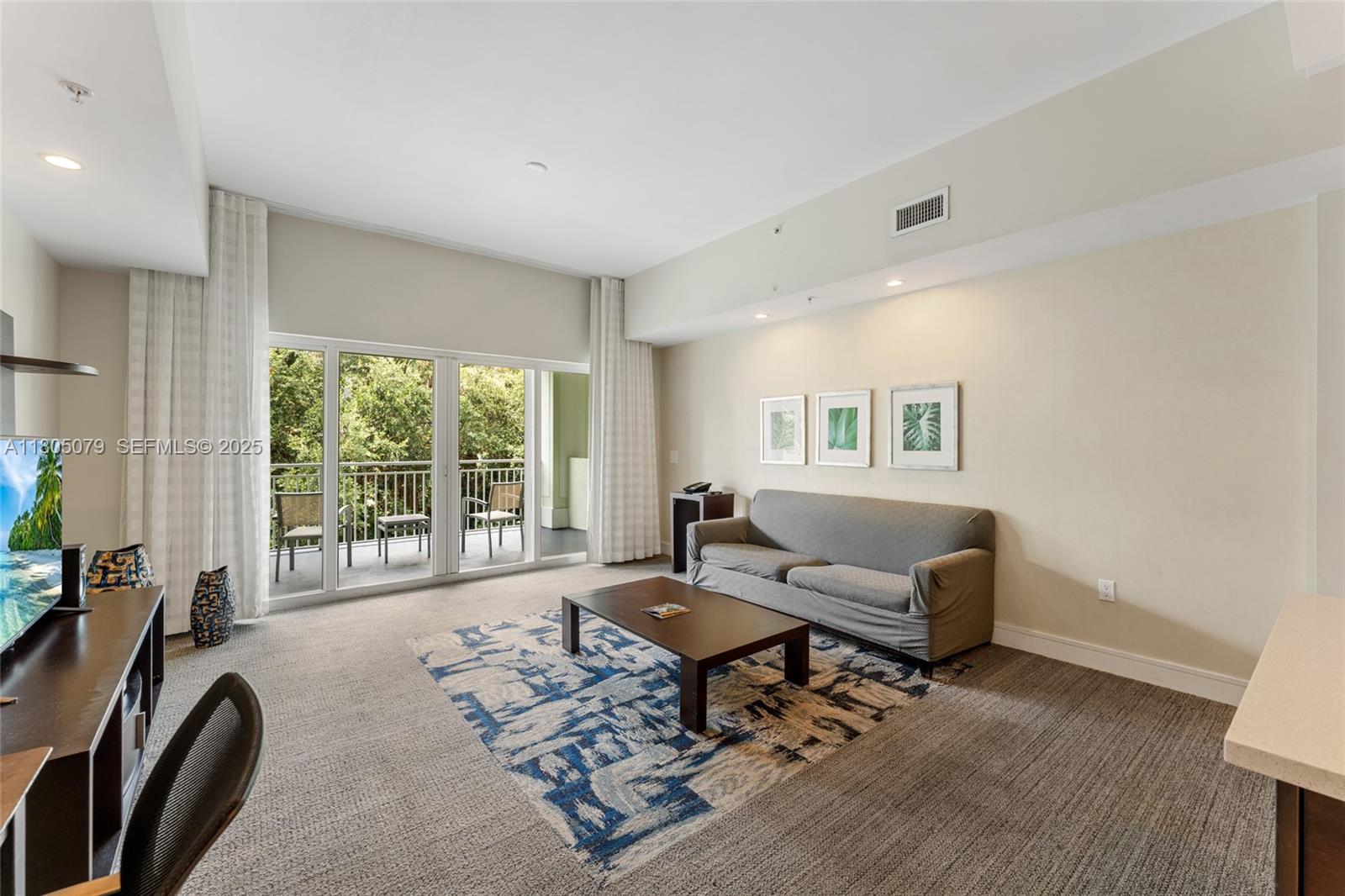 A living room features a gray sofa, a coffee table, and a balcony with trees — 5300 NW 87th Ave # 1513, Doral FL 33178, DORAL, FL