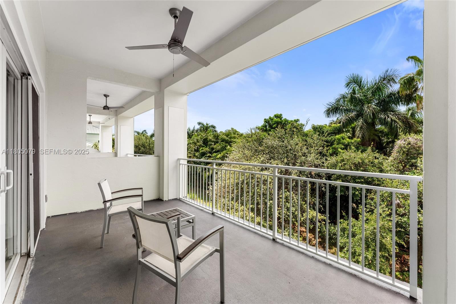 A covered balcony features two chairs, a small table, ceiling fans, and a metal railing — 5300 NW 87th Ave # 1513, Doral FL 33178, DORAL, FL