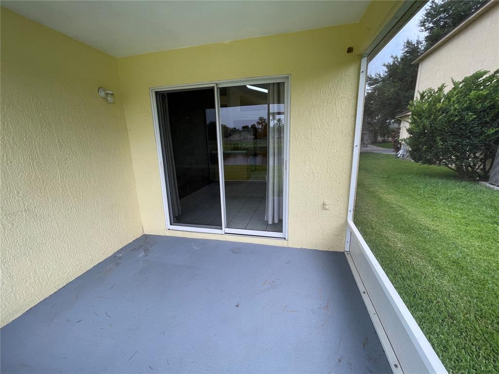 A covered patio with a gray concrete floor, yellow walls, and a sliding glass door — 4219 ANDOVER CAY BOULEVARD, ORLANDO, FL