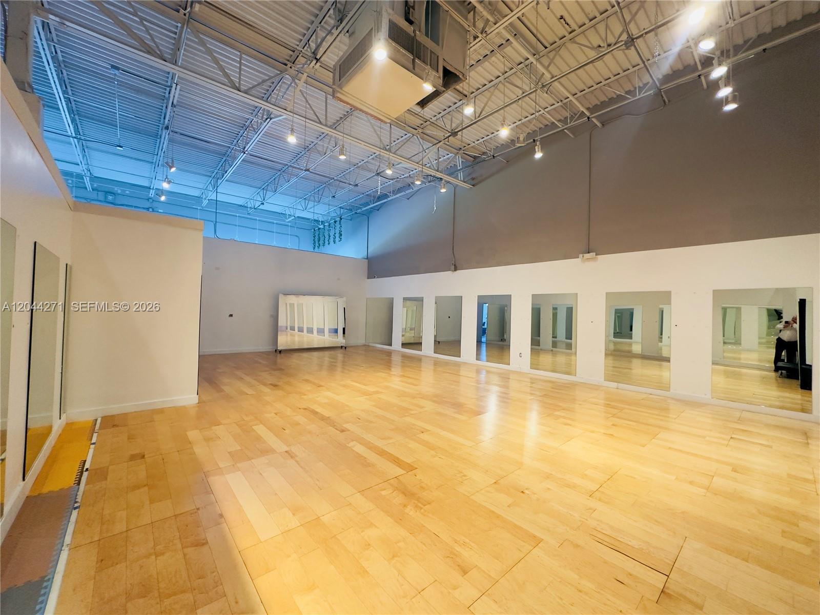 A spacious dance studio features light wood flooring, mirrored walls, and an exposed industrial ceiling — Confidential, North Miami Beach FL 33160, NORTH MIAMI BEACH, FL