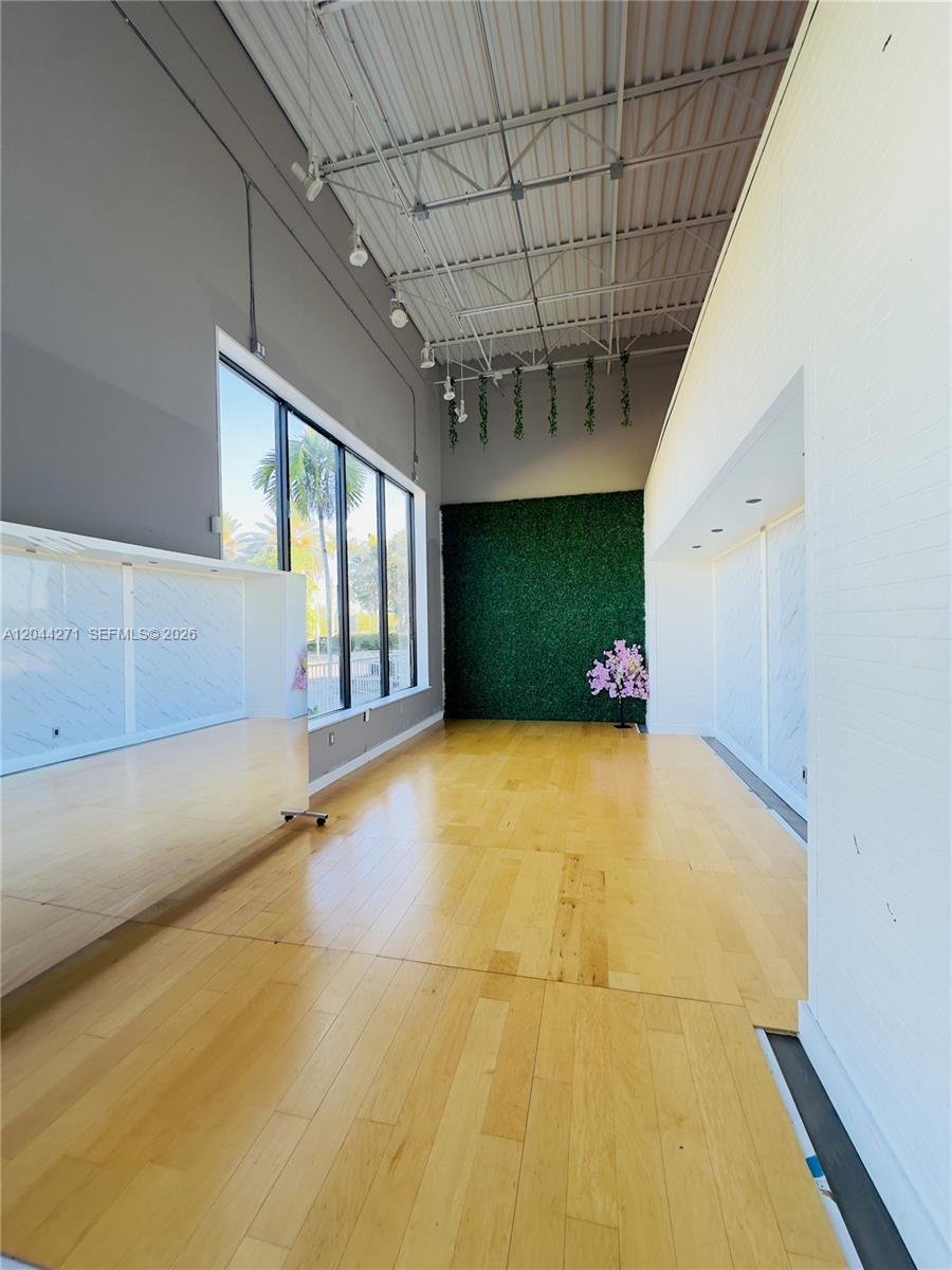 This room features light wood flooring, a green wall, large windows, and an exposed ceiling — Confidential, North Miami Beach FL 33160, NORTH MIAMI BEACH, FL