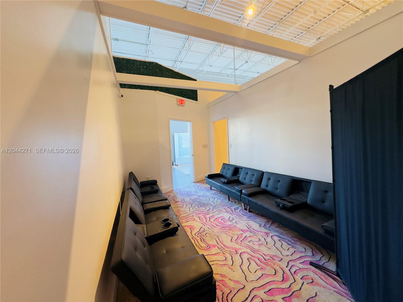 A room with black futons, a patterned rug, and an open ceiling with white beams — Confidential, North Miami Beach FL 33160, NORTH MIAMI BEACH, FL