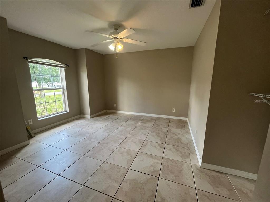 An empty room with beige walls, tile flooring, a ceiling fan, and a single window — 3605 CABALLERO AVENUE, NORTH PORT, FL