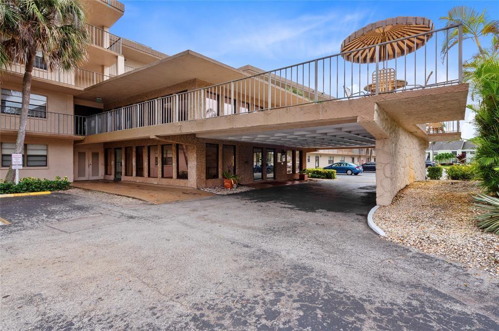 An exterior view of a multi-story apartment building with a covered parking area and balcony — 9300 SW 8th Street # 422, Boca Raton FL 33428, BOCA RATON, FL
