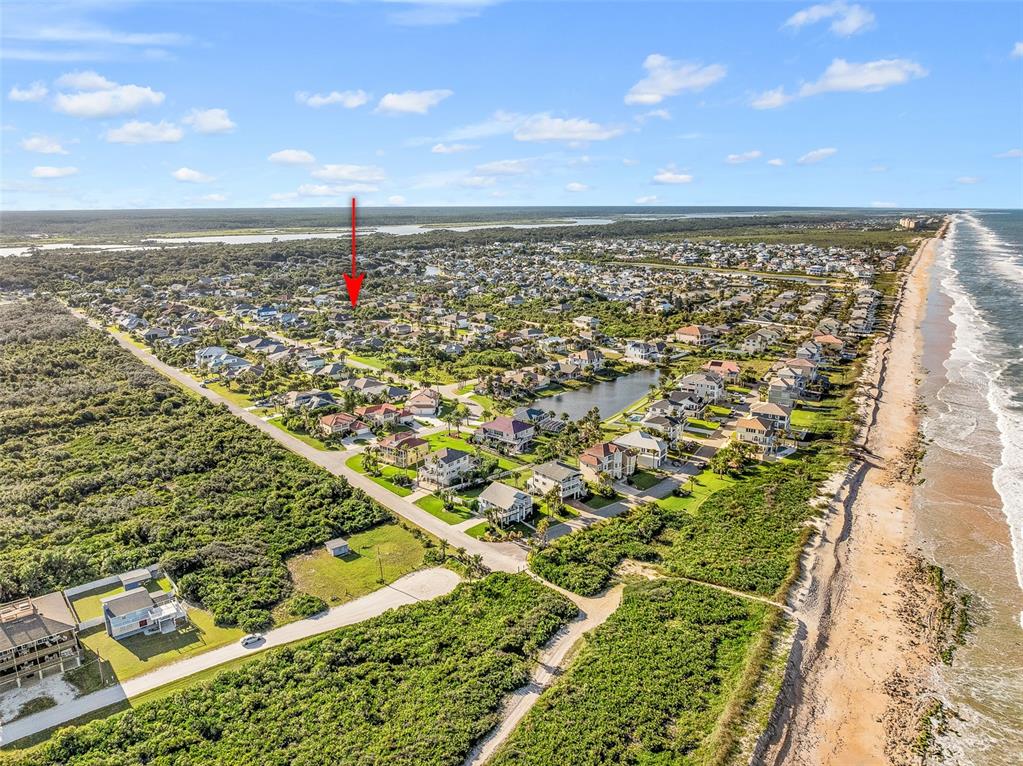 An aerial view shows a coastal neighborhood with a red arrow pointing toward a house — 12 LAUREL DRIVE, PALM COAST, FL