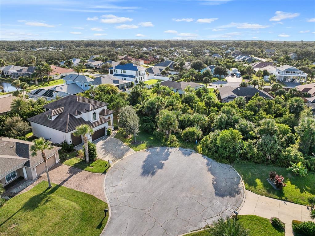 An aerial view shows a suburban cul-de-sac with houses surrounded by dense green trees — 12 LAUREL DRIVE, PALM COAST, FL