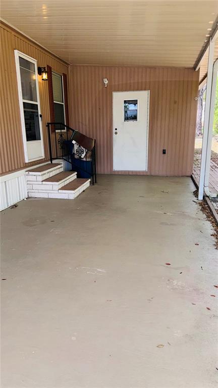 A covered concrete patio features a white door, a window, and small brick steps — 8239 RIDGE DALE AVENUE, BROOKSVILLE, FL
