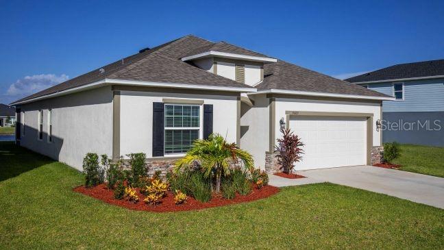 A single-story house with a white stucco exterior, a shingled roof, and a front lawn — 31412 MALBEC DRIVE, BROOKSVILLE, FL