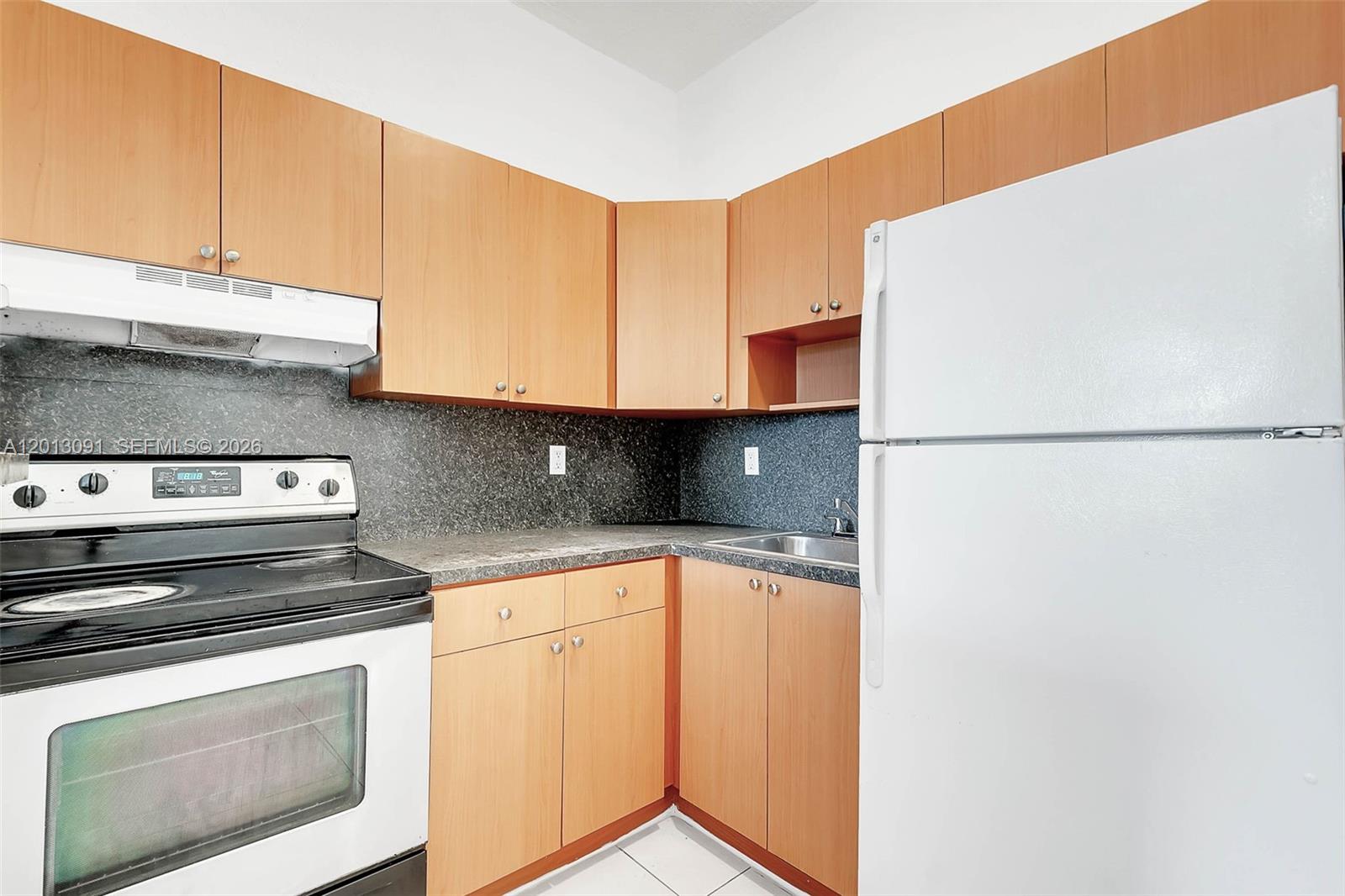 A kitchen features light wood cabinets, a white stove, a white refrigerator, and dark countertops — 50 NW 79th St # 4, Miami FL 33150, MIAMI, FL