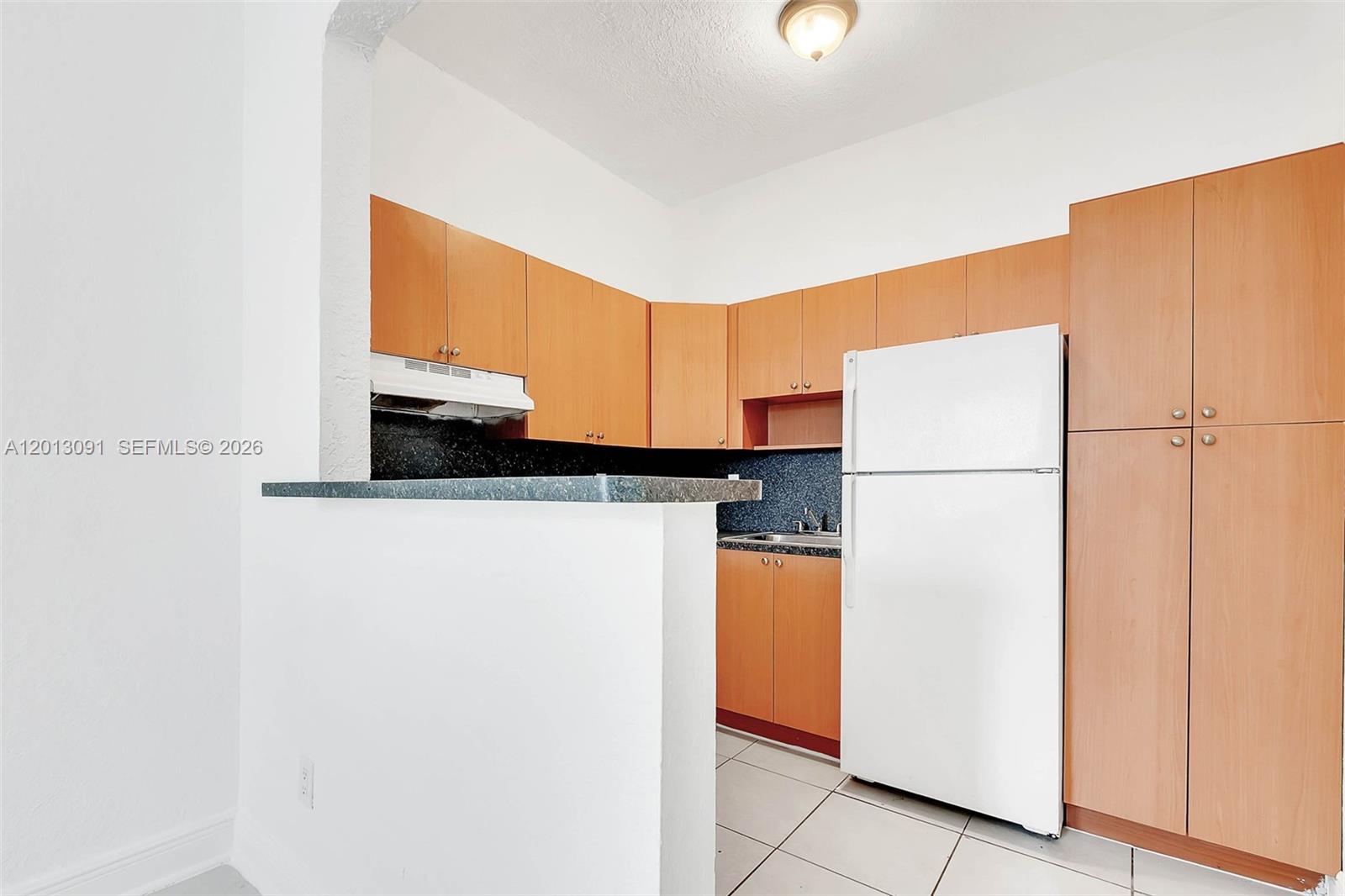 A kitchen features light wood cabinets, a white refrigerator, and a dark countertop — 50 NW 79th St # 4, Miami FL 33150, MIAMI, FL